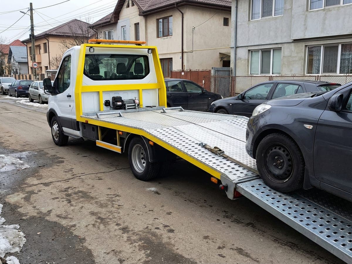 Platformă de tractare înclinată încarcând un vehicul pe stradă